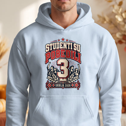 A man wearing a light blue hooded sweatshirt featuring a red, white, and black graphic with the text "STUDENTI SU POBEDILI 3 SRBIJA 2026".