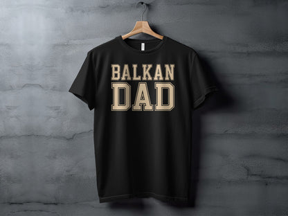 Black t-shirt with beige text reading "BALKAN DAD" hangs on a wall.