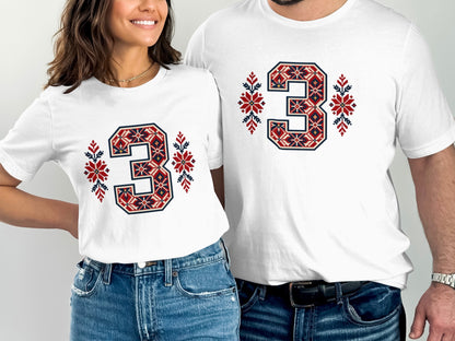 A man and woman wear matching white t-shirts featuring a red and blue Nordic-patterned number 3 design.