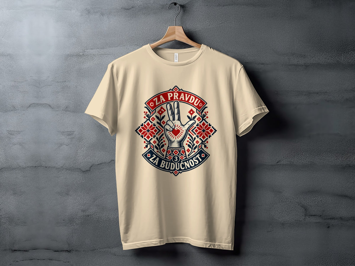 Beige t-shirt hanging on a wooden hanger against a textured gray wall, featuring a Serbian folk-style graphic with a three-finger salute and text.
