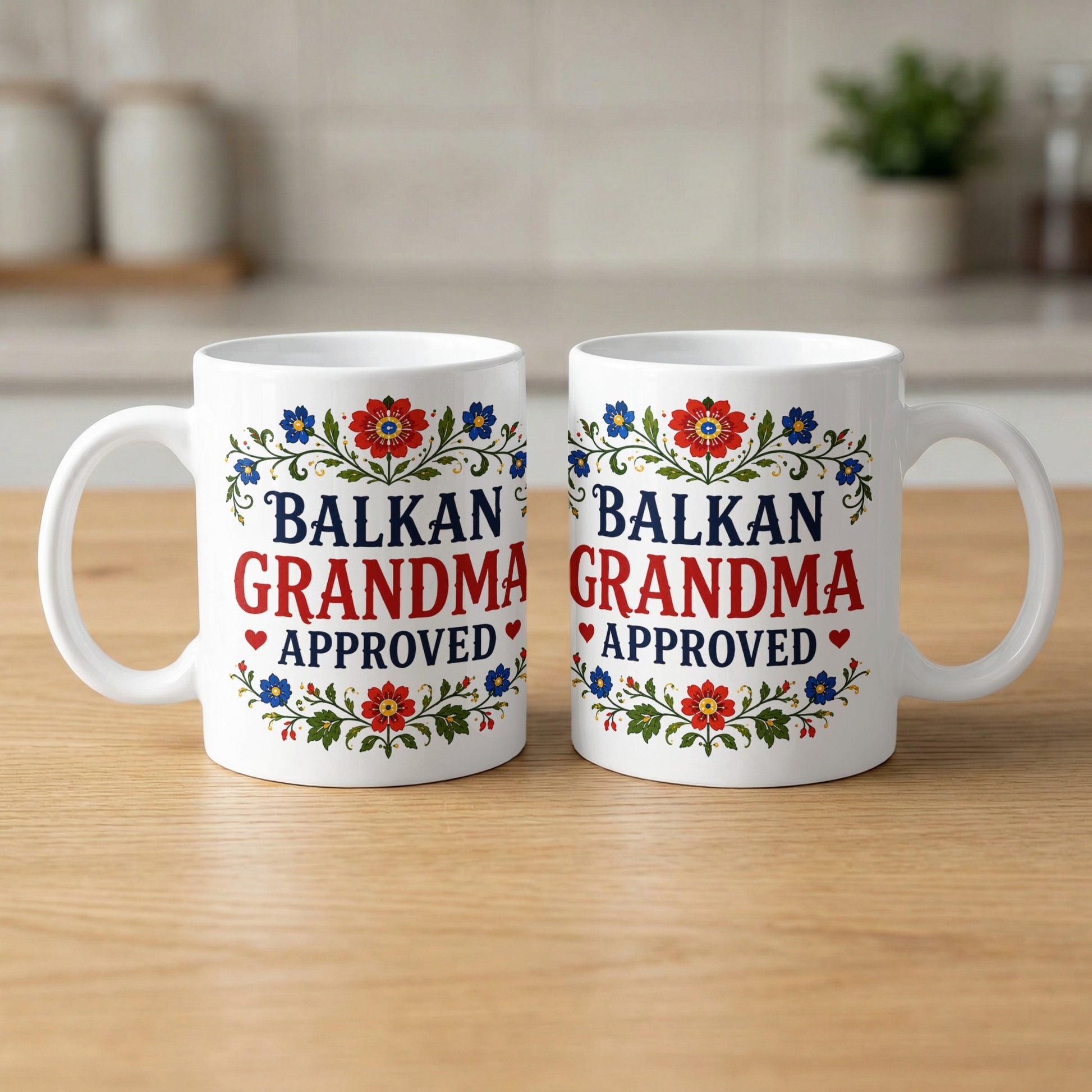 Two white mugs with floral designs, reading "Balkan Grandma Approved".