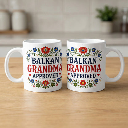 Two white mugs with floral designs, reading "Balkan Grandma Approved".