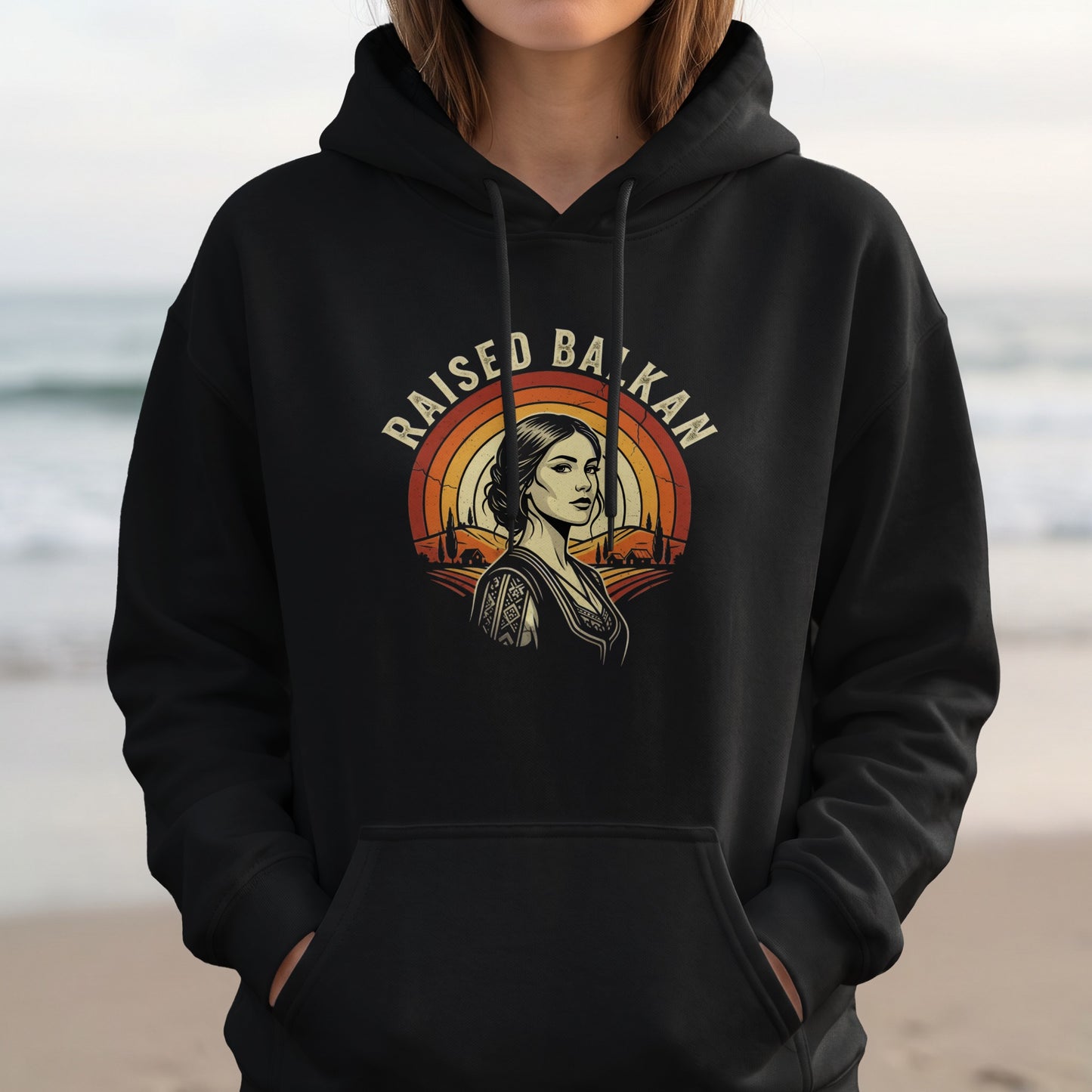 Black hoodie with "Raised Balkan" text and a woman's portrait with a rainbow background.