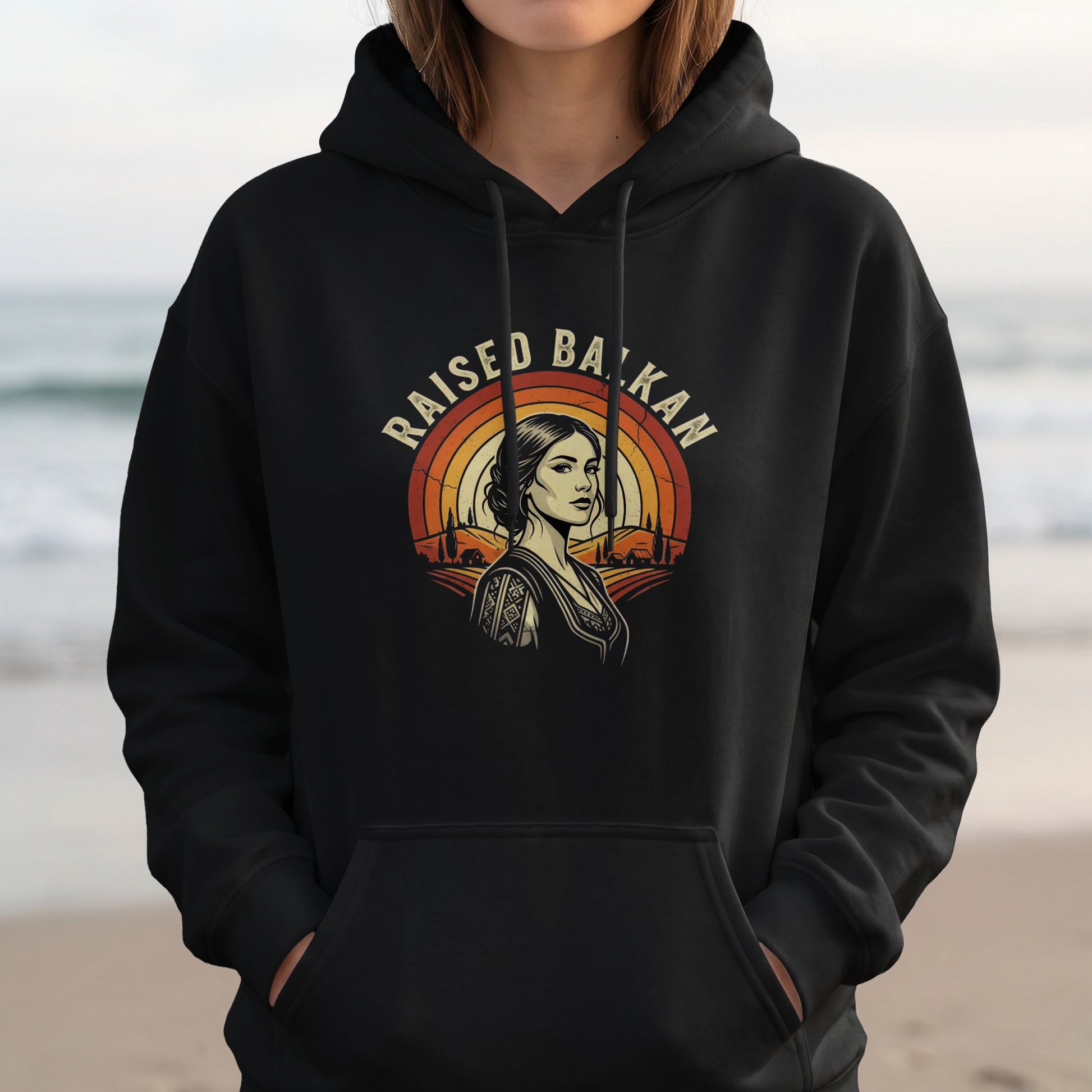 Black hoodie with "Raised Balkan" text and a woman's portrait with a rainbow background.