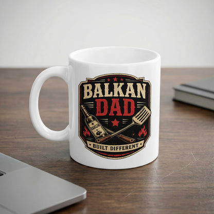 White mug with "BALKAN DAD BUILT DIFFERENT" text and grilling tools.
