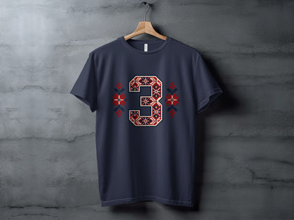 A dark blue t-shirt hanging on a wooden hanger features a large, red and white Nordic-style number three graphic with matching snowflake accents.