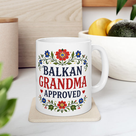 White mug with "Balkan Grandma Approved" text and floral design.