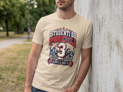 A man wearing a beige t-shirt featuring a blue and red graphic with the text STUDENTS SU POBEDILI.