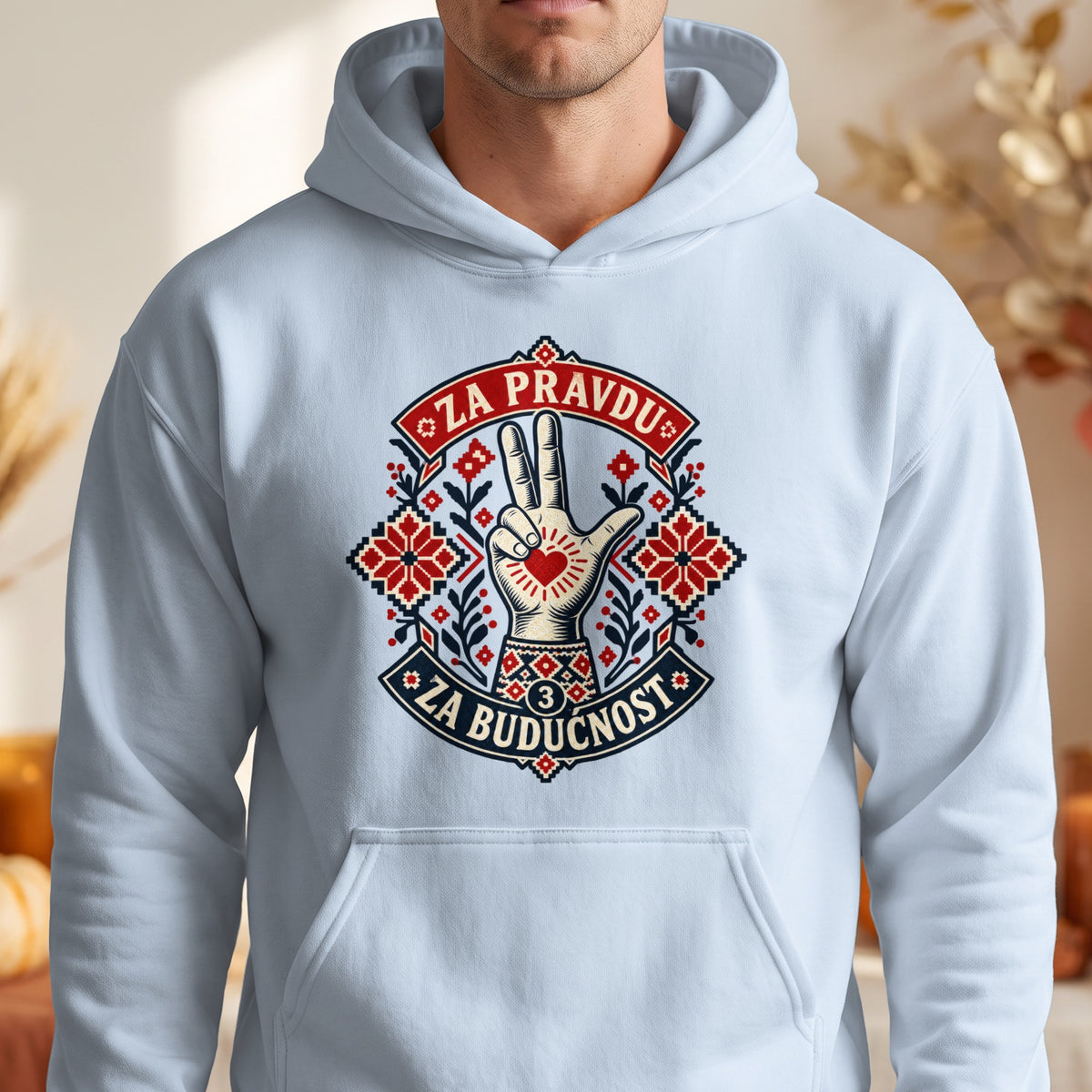 A light blue hooded sweatshirt features a centered graphic with a three-finger salute, traditional red embroidery patterns, and the text ZA PRAVDU and ZA BUDUCNOST.