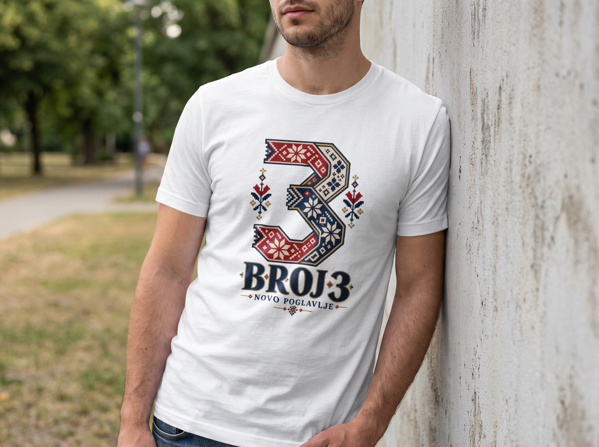 A man leans against a concrete wall wearing a white t-shirt featuring a large number three in red and blue folkloric patterns, with text below reading BROJ 3 NOVO POGLAVLJE.