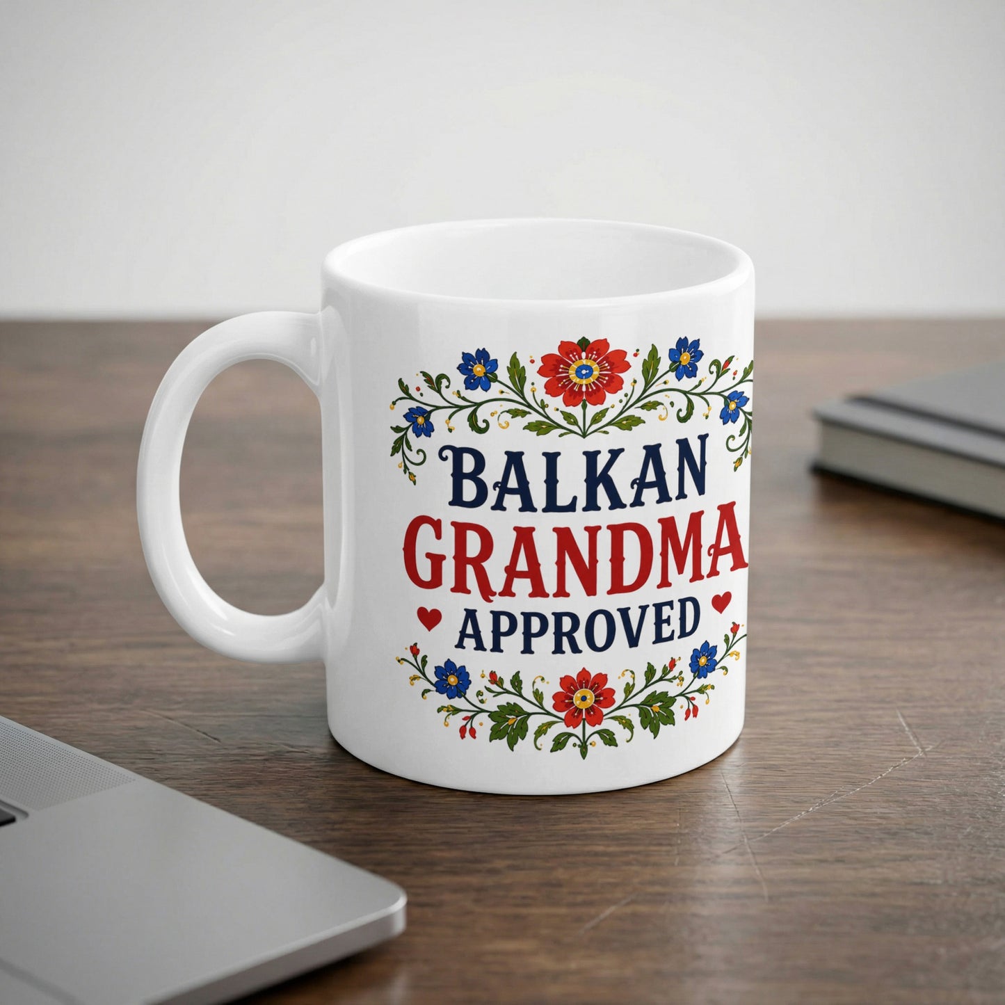 White mug with blue and red floral design and text "BALKAN GRANDMA APPROVED".