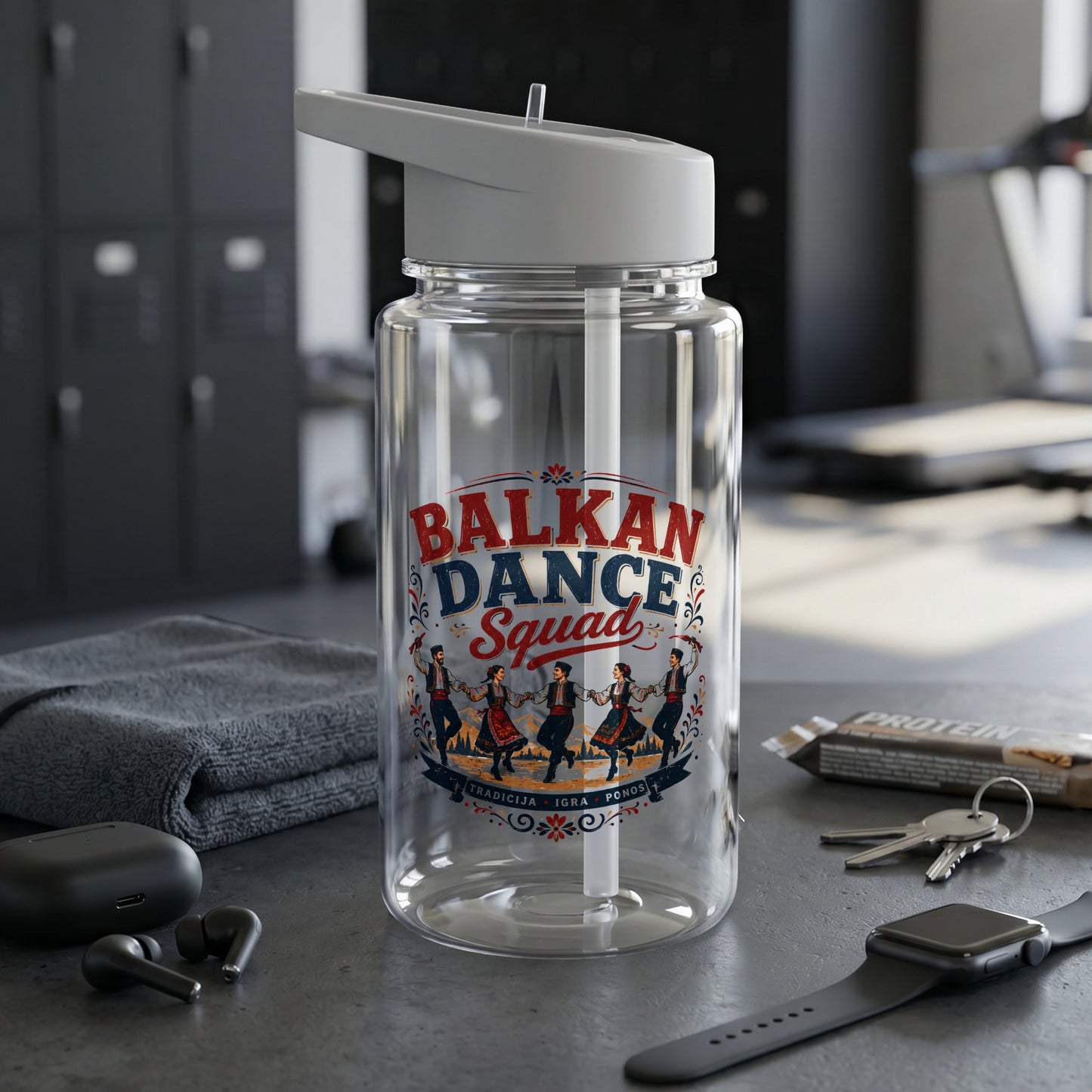 Clear water bottle with "Balkan Dance Squad" logo, gym setting and accessories.