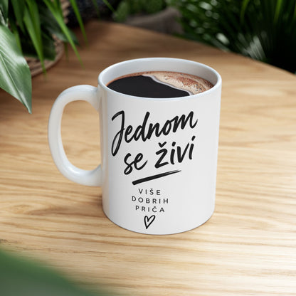 White mug with black text "Jednom se živi" and "Više dobrih priča" and heart.
