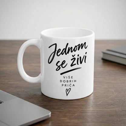 White mug with black text reading "Jednom se živi" and "VIŠE DOBRIH PRIČA".