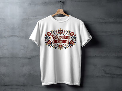 A white t-shirt on a wooden hanger with a decorative floral illustration and Serbian text reading "Nek puknu dušmani".