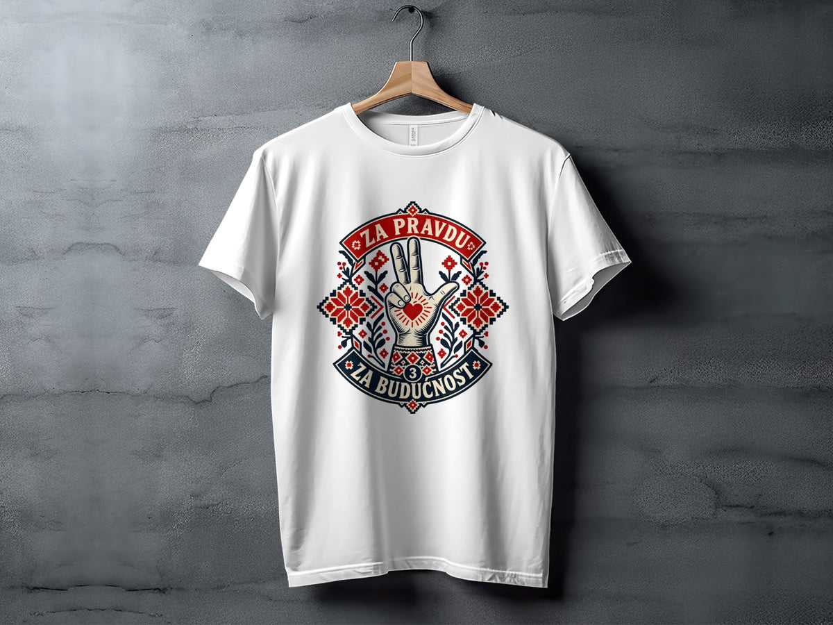 A white t-shirt hangs on a wooden hanger against a textured gray background, featuring a graphic with Serbian Cyrillic text and traditional folk motifs.