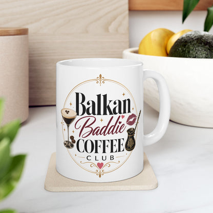 White mug with "Balkan Baddie Coffee Club" text and coffee-themed graphics.