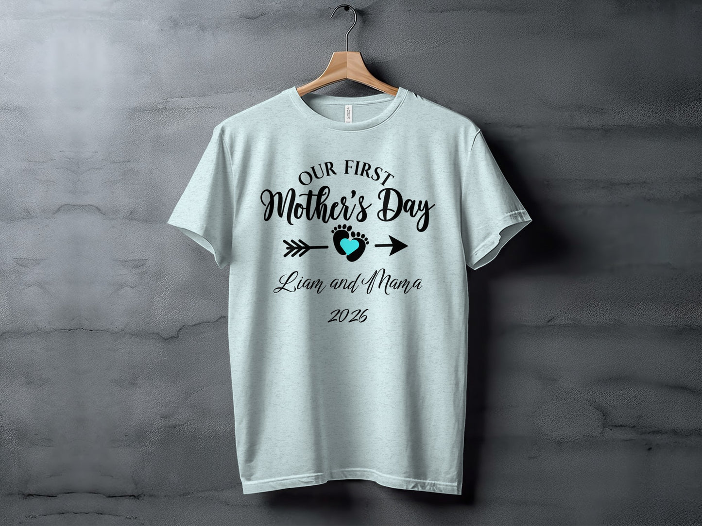 Light blue t-shirt with "Our First Mother's Day" text and baby footprint design.