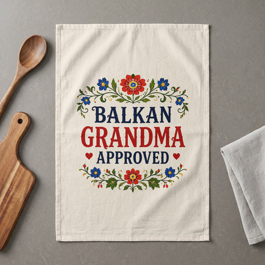 Balkan Grandma Approved text on a cream kitchen towel with floral accents.