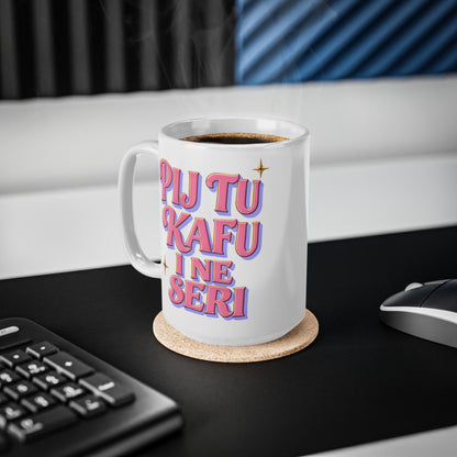White mug with pink and purple text reading "PIJ TU KAFU I NE SERI" on a desk.