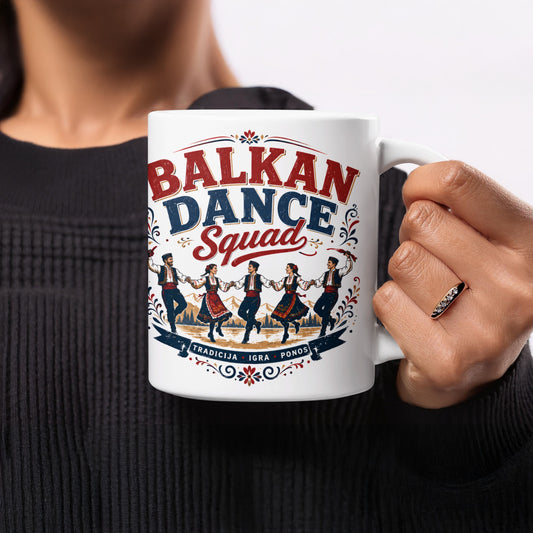 White mug with "BALKAN DANCE SQUAD" text and people in traditional clothing dancing.