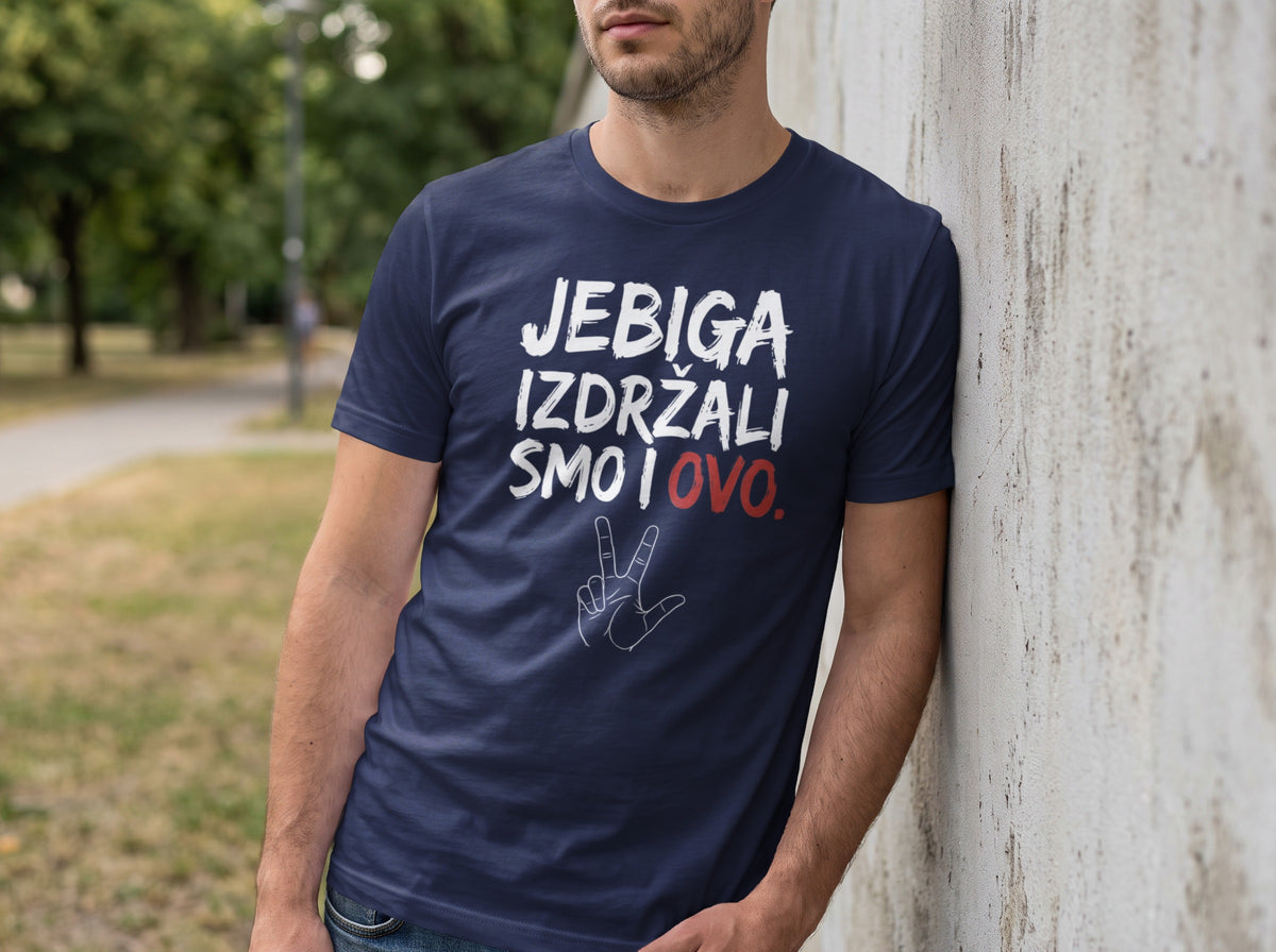 A man leans against a concrete wall wearing a dark blue t-shirt with white and red text.