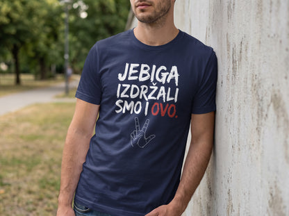 A man leans against a concrete wall wearing a dark blue t-shirt with white and red text.