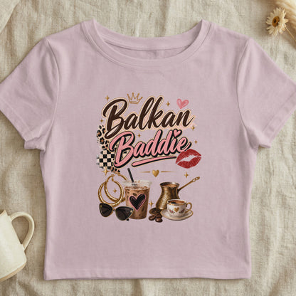 Pink t-shirt with "Balkan Baddie" text, crown, heart, lips, coffee, and accessories.