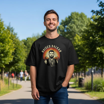 Black t-shirt with "RAISED BALKAN" text and a man in traditional vest.