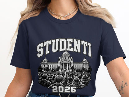 A person wearing a dark blue t-shirt featuring the text "STUDENTI 2026" above an illustration of a large crowd protesting in front of a government building.