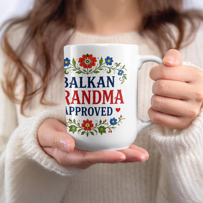 White mug with "BALKAN GRANDMA APPROVED" text and floral design.