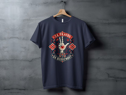 A dark grey t-shirt hanging on a wooden hanger features a graphic with a hand showing a three-finger salute surrounded by traditional folk embroidery patterns and text.