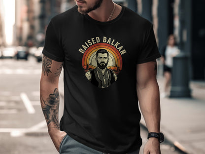 Black t-shirt with "Raised Balkan" text and a man in traditional clothing design.