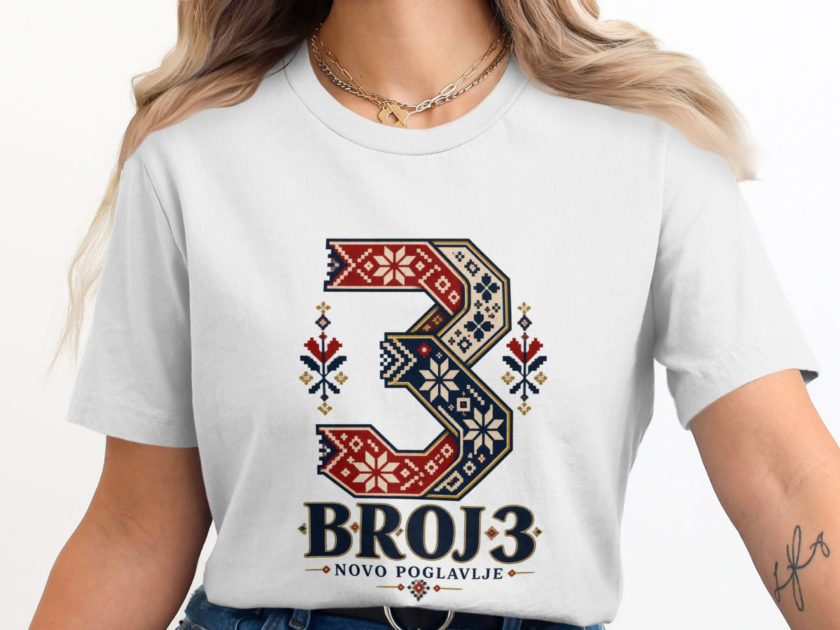 A woman wearing a white t-shirt featuring a stylized number three in traditional folk embroidery patterns.