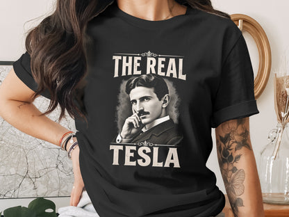 Black t-shirt with "THE REAL TESLA" text and a portrait of Nikola Tesla.