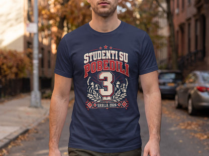 A man wearing a dark blue t-shirt featuring the graphic text "STUDENTI SU POBEDILI 3 SRBIJA 2026."