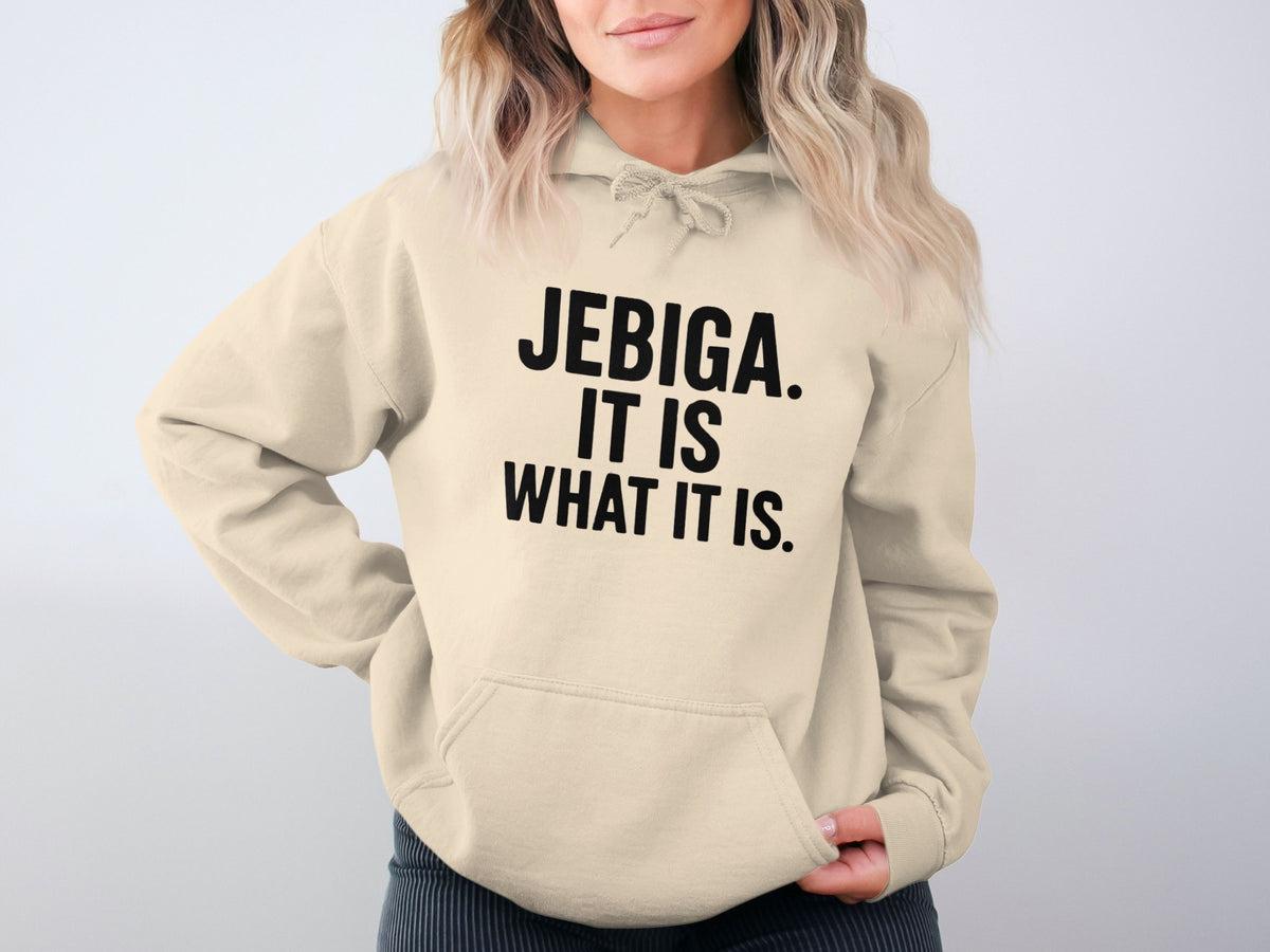 Cream hoodie with black text reading "Jebiga. It is what it is."