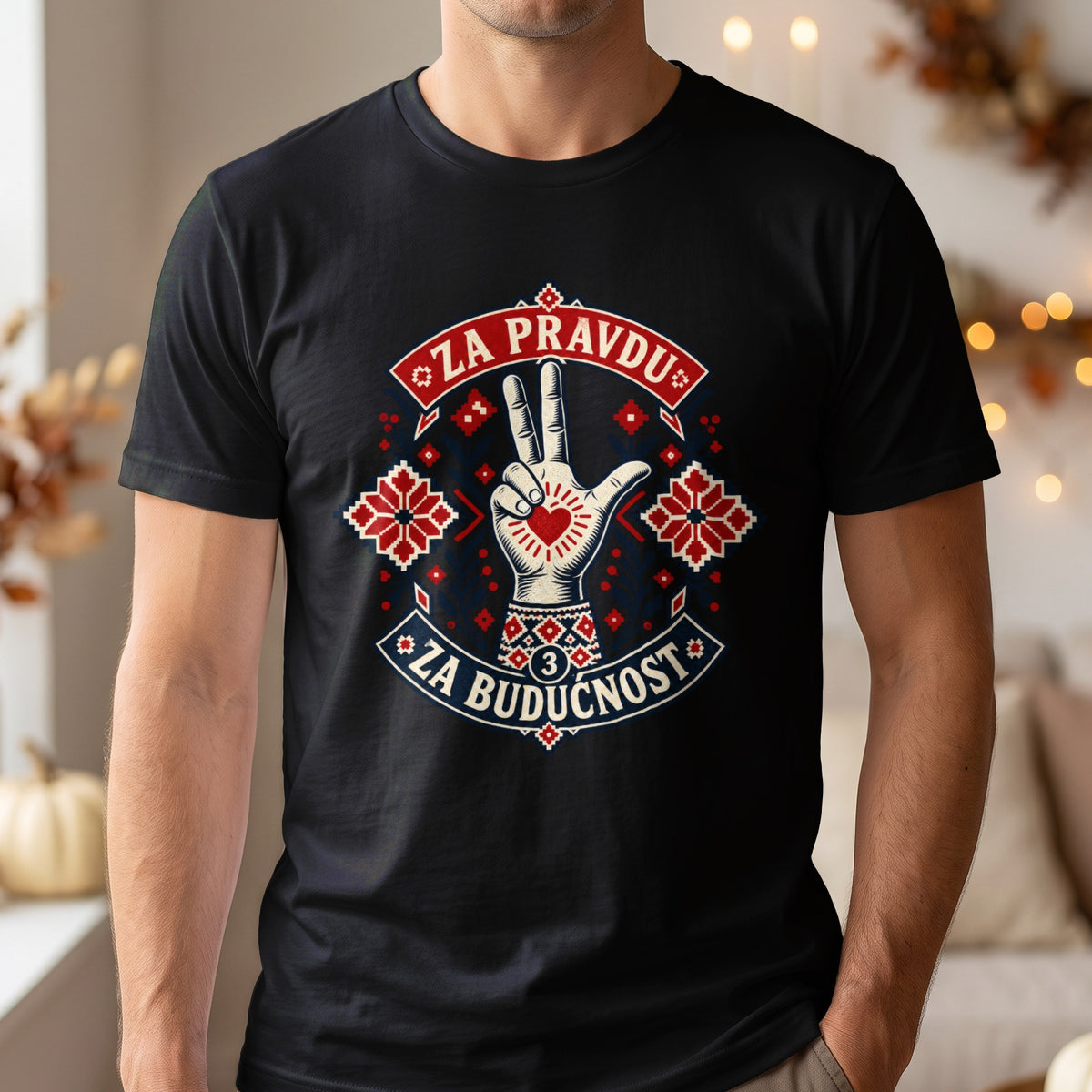 A person wearing a black t-shirt with a graphic design featuring a hand making a three-finger salute, traditional red and blue embroidery patterns, and the text ZA PRAVDU ZA BUDUCNOST.