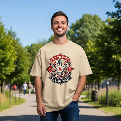 A smiling man wearing a beige t-shirt with a red and blue graphic design on an outdoor path.