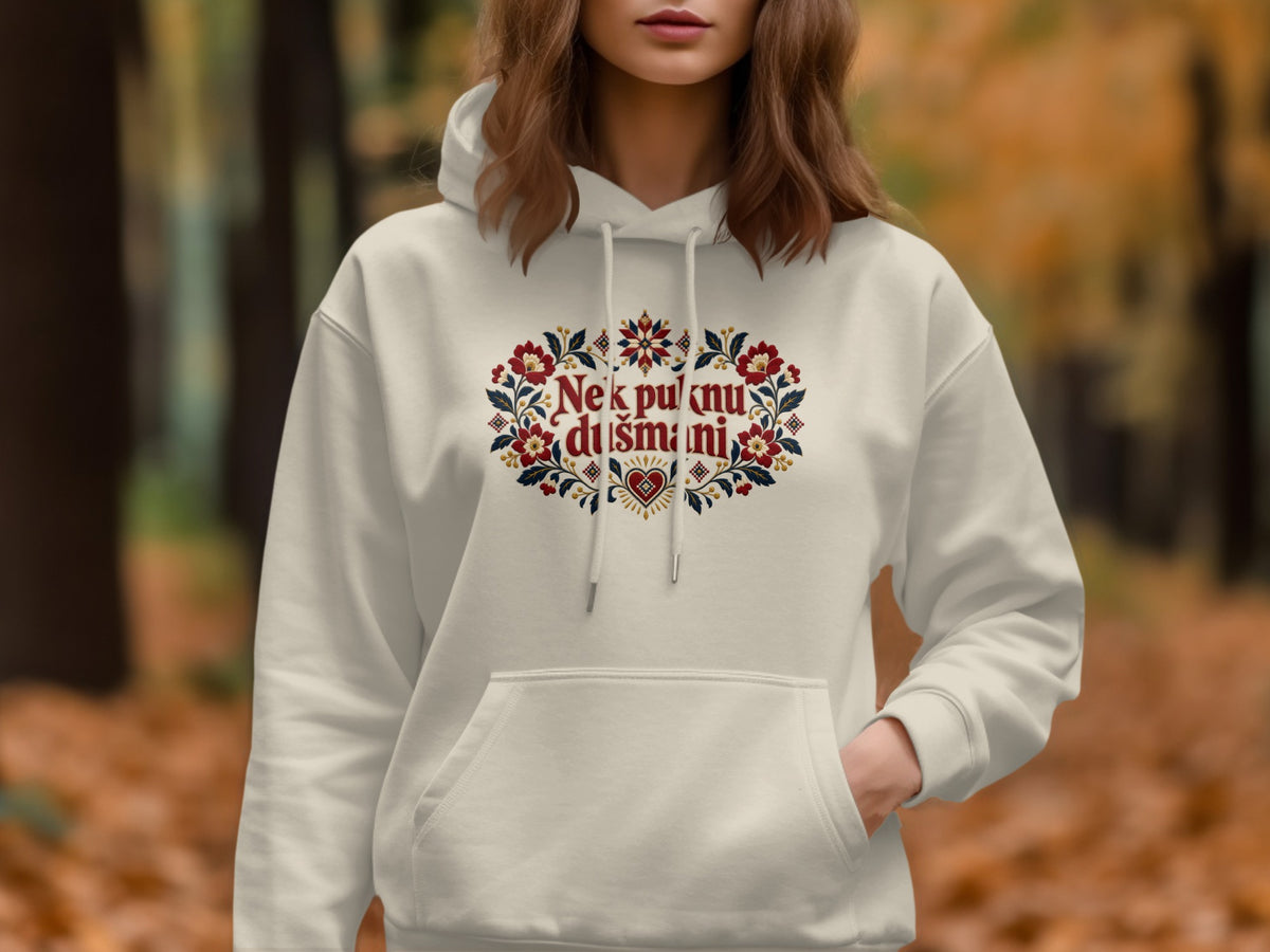 A person wears an off-white hoodie featuring a colorful floral chest embroidery with red text.