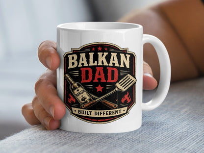 White mug with "Balkan Dad Built Different" text and grill tools.