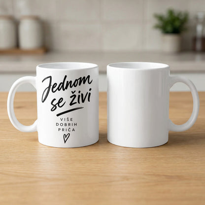 White mug with text "Jednom se živi" and "VIŠE DOBRIH PRIČA" and a heart.