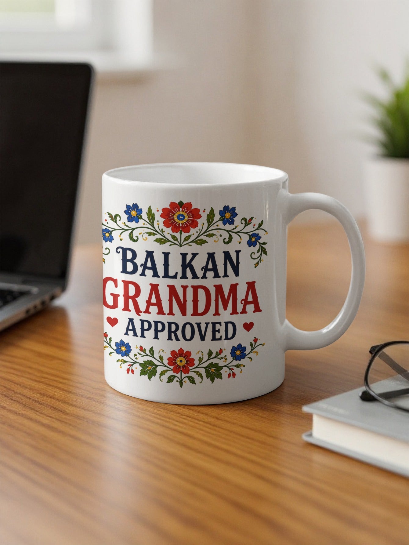 White mug with "BALKAN GRANDMA APPROVED" text and floral design.