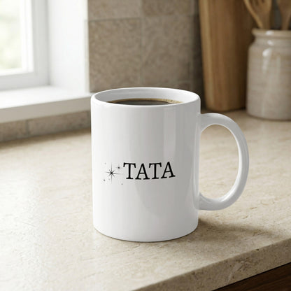 White mug with "TATA" in black text and small star accents.