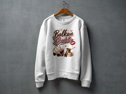 White sweatshirt with "Balkan Baddie" text and graphic elements of coffee, sunglasses, and lipstick.