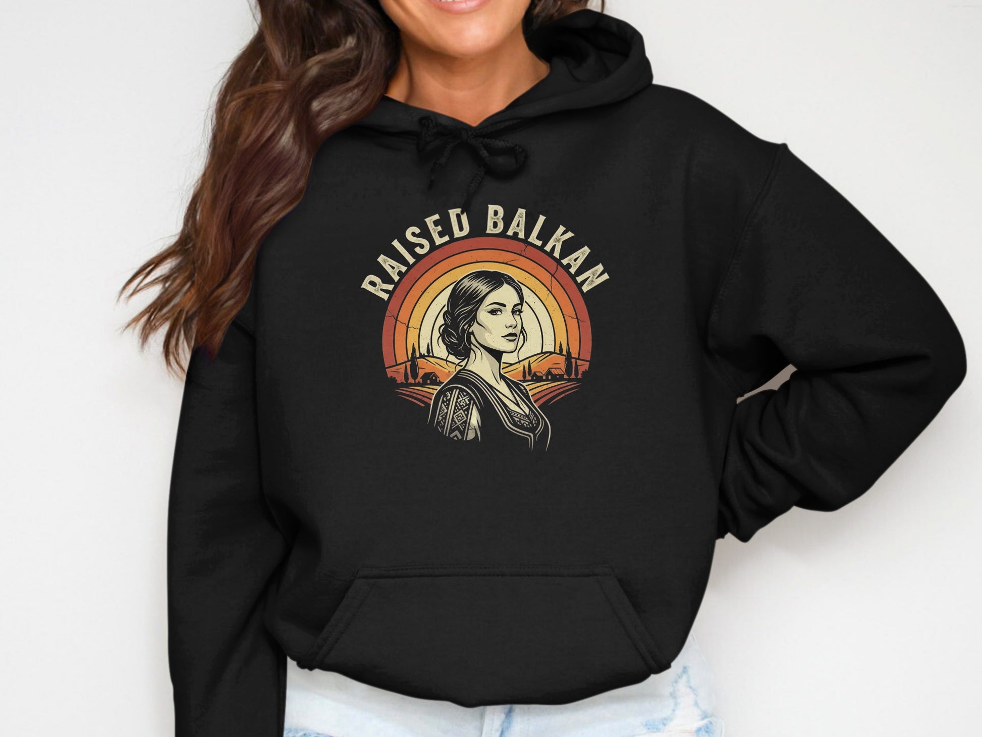 Black hoodie with "Raised Balkan" text and woman in traditional clothing.