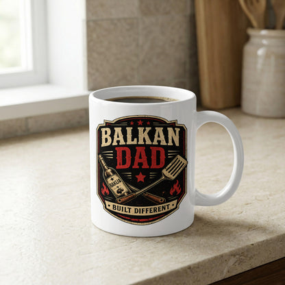 Mug with "Balkan Dad Built Different" text, spatula, and grill graphic.