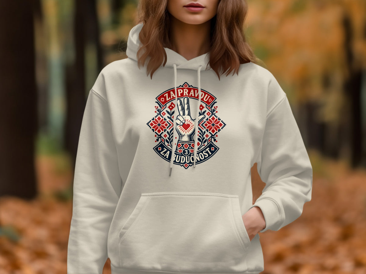 A woman wearing a cream-colored hooded sweatshirt featuring a red, white, and blue embroidered graphic on the chest.