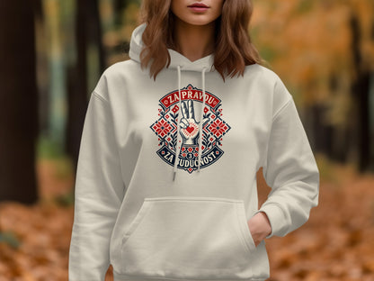 A woman wearing a cream-colored hooded sweatshirt featuring a red, white, and blue embroidered graphic on the chest.