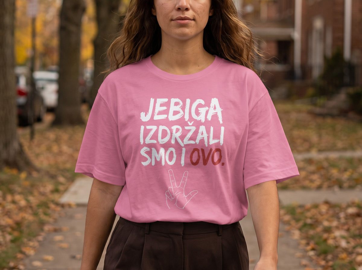 A woman with long wavy hair wears a pink t-shirt with Serbian text and a hand symbol.